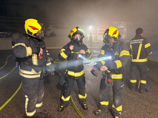 Feuerwehrleute in Schutzausrüstung mit Atemschutzmasken und Stirnlampen bei einem Einsatz in Windhaag