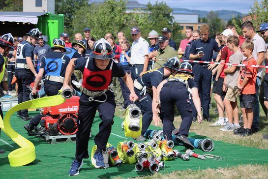 Jugendliche Feuerwehrleute bei einem Bewerb in Österreich mit Schläuchen und Spritze